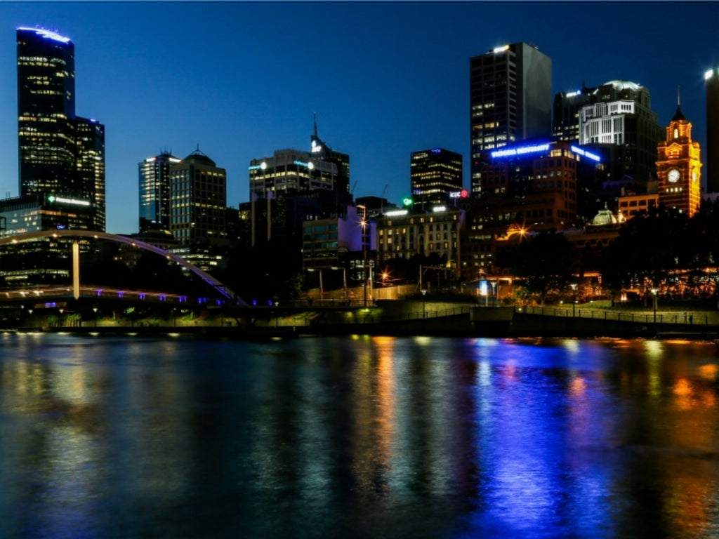 Melbourne CBD skyline at night with Flinders Street Station clock tower, lit-up buildings and reflections on Yarra River, Victoria, Australia