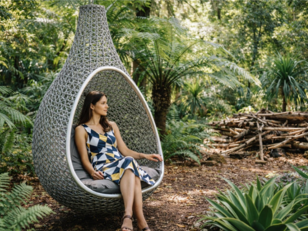 Woman relaxing in a modern hanging chair amidst ferns and native Australian plants at Royal Botanic Gardens Cranbourne